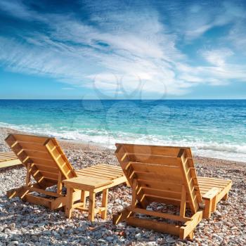 Two wooden sun loungers stand on the beach in Montenegro