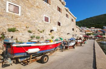 Red fishing boat stands on the coast in Petrovac, Montenegro