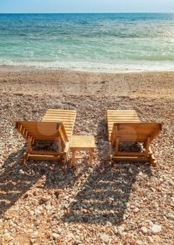 Two wooden sun loungers stand on the Adriatic Sea coast
