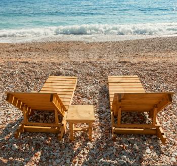 Wooden sun loungers stand on the Adriatic Sea coast