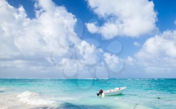 Small white motor boat floats moored near the coast of Atlantic ocean in Dominican republic. Punta Cana