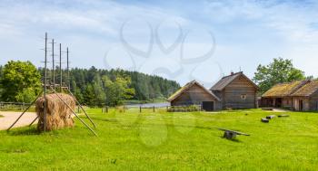 Russian rural landscape with old wooden houses and barns on green meadow