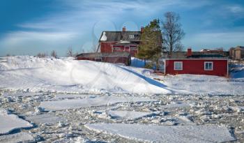Classical Scandinavian village on the coast of frozen winter lake
