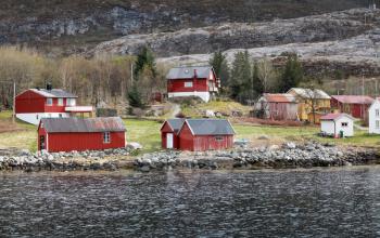 Traditional Norwegian small village with red wooden houses on rocky coast in spring