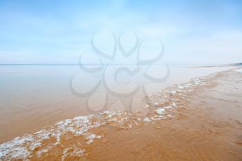 Ice fragments on empty sandy coast of Baltic Sea