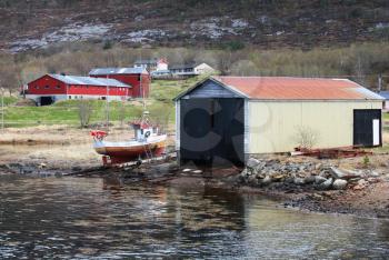 Traditional Norwegian wooden barns and small fishing boat on the sea coast
