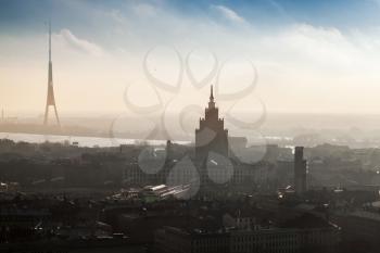 RIGA, LATVIA - DECEMBER 31, 2013: Cityscape panorama of Riga town with tall living house and TV tower in the fog on the coast of Daugava River