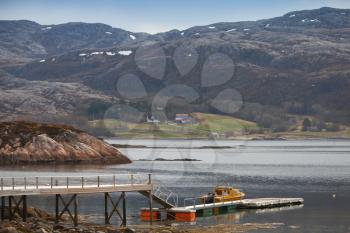 Norwegian landscape. Small motor boat stands moored near floating pier