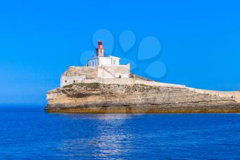 Madonetta, lighthouse tower with red top on coastal rock. Bonifacio port. Mountainous Mediterranean island Corsica, Corse-du-Sud, France