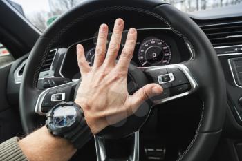 Driver angry pushes a steering wheel klaxon of luxury car. Closeup photo with selective focus