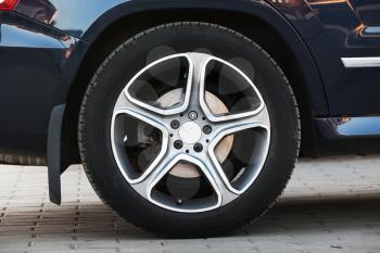 Modern car wheel on light alloy disc, closeup photo