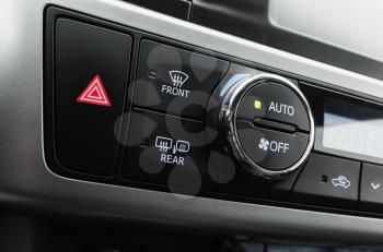 Emergency stop button with red tiangle sign and climate control panel, modern luxury car interior details