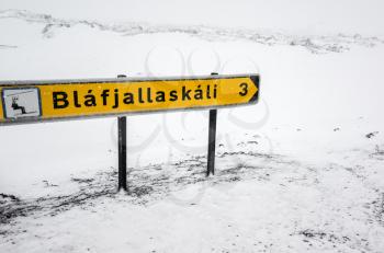 Yellow Icelandic road sign with direction to sky resort stands on the roadside in cold snowy winter day