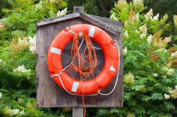 Bright red lifebuoy with ropes hanging in wooden box