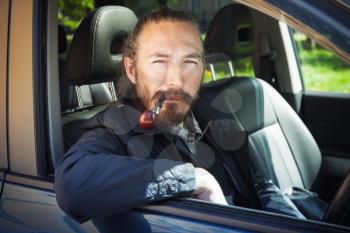 Asian man smoking pipe. Driver of modern Japanese crossover suv car, portrait in open car window