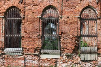 Collapsing red brick facade of an old abandoned church with empty windows