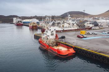 Red tugboat stands moored in port of Vestmannaeyjar island, Iceland