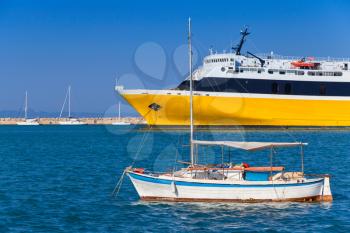 Yellow passenger ferry and small fishing boat anchored in port of Zakynthos, Greek island in the Ionian Sea, popular tourist destination for summer holidays