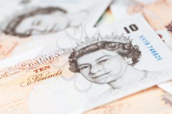 Ten pound notes of the Bank of England lay on a table. Close-up photo with selective focus
