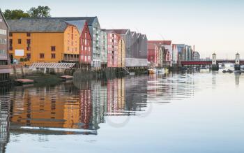 Wooden living houses stand in a row along the river coast. Trondheim, Norway