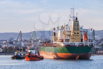 Bulk carrier and tug boats, industrial ship enters in port of Varna, Bulgaria