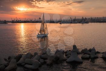 Sailing yacht enters the harbor at sunset. Black Sea, Varna port, Bulgaria