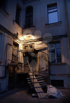 Old door with lamp and wooden stairs at night