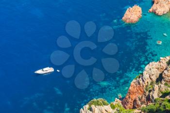 vWhite pleasure boat anchored near rocky coast of Corsica island