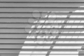 White metal roller shutter door with shadows pattern. Background photo texture, front view