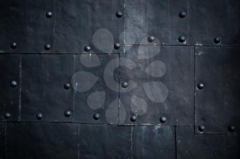 Old black ship hull fragment, grungy metal sheets with rivets, background photo texture