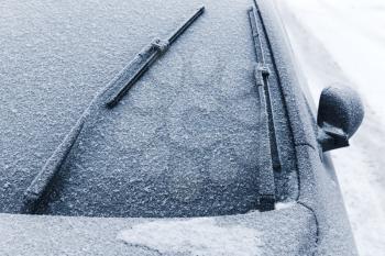 Car wipers on windshield covered with snow in cold winter season