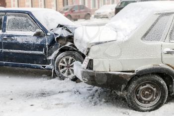 Two crashed cars in accident on winter street with snow