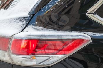 Rear stop lights of SUV car covered with snow, winter season