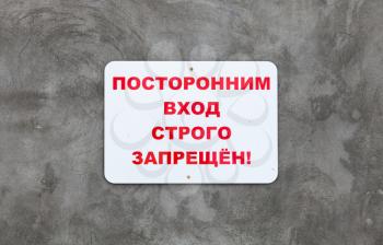 White plate on gray concrete wall with the inscription in Russian: Unauthorized entry is strictly prohibited