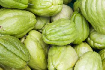 Green Chayote fruits lay on the counter of street food market on Madeira island, Portugal. Close-up photo with selective focus
