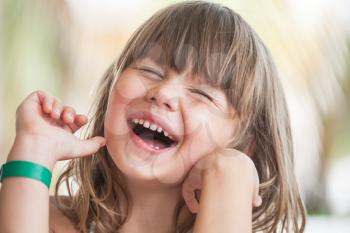 Laughing Blond Caucasian little girl, close-up outdoor face portrait