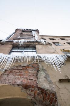 Large icicles hang on the facade of old living house. Winter in Saint-Petersburg, Russia