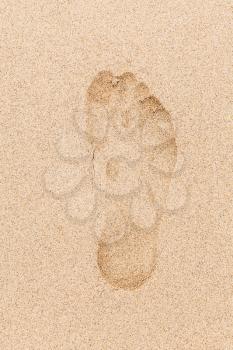 Human footprint in wet yellow sand on the beach