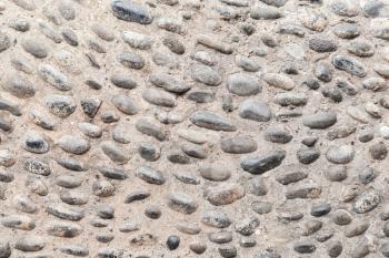 Old road pavement with round pebble in concrete base