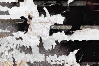 Grunge concrete wall with peeling paint and paper layers, close-up background photo texture
