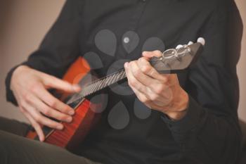Russian folk music background. Hands of a man playing balalaika, close-up photo with selective focus and motion blur effect