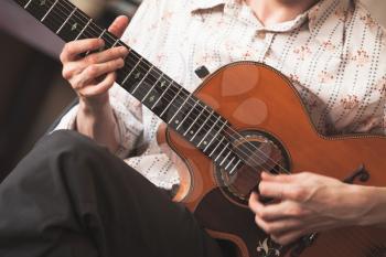 Live music background. Acoustic guitar player, close-up photo with selective focus on hands 
