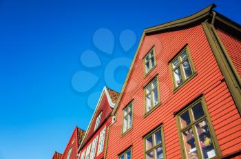 Traditional Norwegian red wooden houses under deep blue sky, Bergen Bryggen                                     