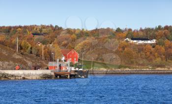 Autumn Norwegian landscape, red wooden houses near pier on seacoast