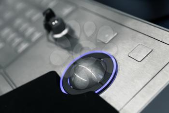 Industrial control panel made of gray metal with blue trackball and security lock key, close up photo with soft selective focus