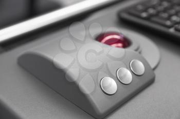 Industrial keyboard made of gray metal with red trackball, close up photo with soft selective focus