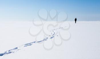 Footsteps of lonely person walking on frozen sea covered with snow