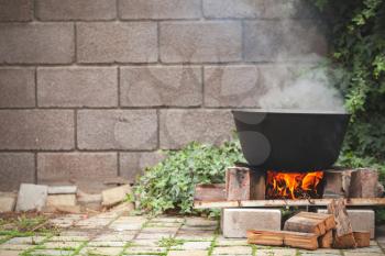 Black cauldron is on a bonfire. Outdoor preparing of Chorba