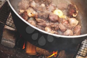 Lamb pieces and vegetables are in a cauldron. Preparing of Chorba soup on open fire, traditional meal for many national cuisines