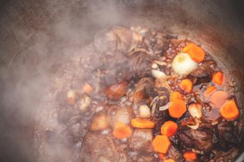 Lamb with vegetables stew in a cauldron. Preparing of Chorba soup on open fire